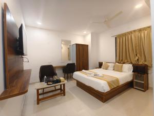 a bedroom with a bed and a tv and a table at Hotel Vamshi Grand in Lingampalli