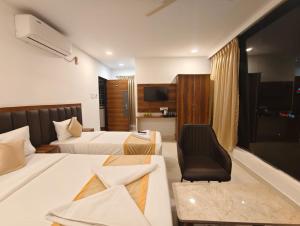 a hotel room with two beds and a chair at Hotel Vamshi Grand in Lingampalli +23 photos