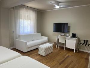 a living room with a white couch and a tv at Hotel 1908 in Forte dei Marmi