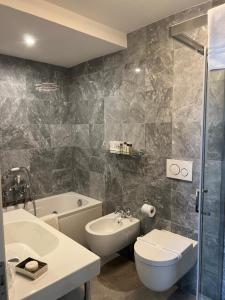 a bathroom with a sink and a toilet and a tub at Hotel 1908 in Forte dei Marmi