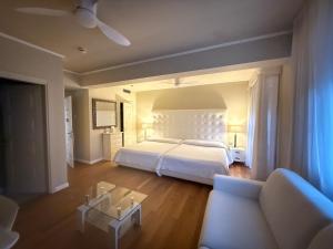 a bedroom with a white bed and a couch at Hotel 1908 in Forte dei Marmi