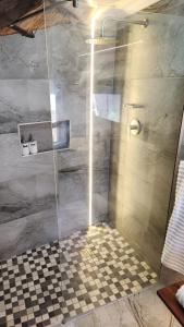 a shower with a glass door and a checkered floor at Bootleg Inn in Welkom