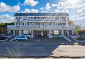 a white building with two cars parked in a parking lot at 19 Lagoon Terrace in Knysna