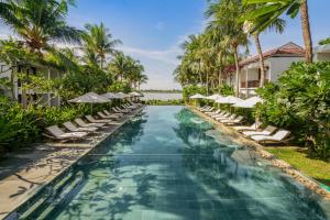 a pool at the resort with lounge chairs and umbrellas at Emerald Hoi An Riverside Resort in Hoi An