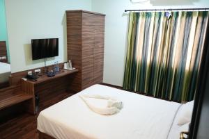 a hotel room with a bed and a television at Royal Homes in Tallākulam