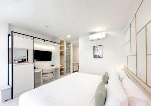 a white bedroom with a bed and a tv at Tatami Hotel Phuket in Ban Ket Ho