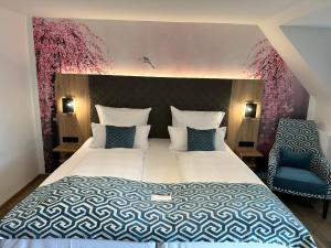 a bedroom with a large bed and a blue chair at Akzent Hotel Köhler in Gießen +77 photos