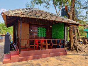 a small house with red chairs in front of a tree at patanga beach cottege in Gokarna