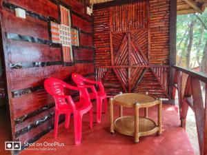three red chairs and a table in a room at patanga beach cottege in Gokarna