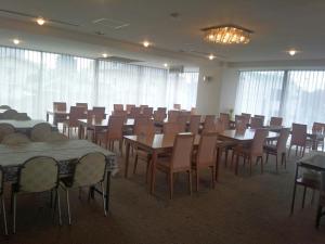 uma sala de jantar com mesas, cadeiras e janelas em Mito Riverside Hotel em Mito