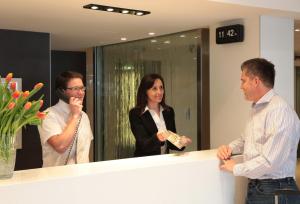 a group of people standing around a reception counter at Hôtel Alba in Lourdes +28 photos