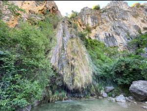 a waterfall on the side of a mountain next to a river at Poseidón in Quesada +1 photo