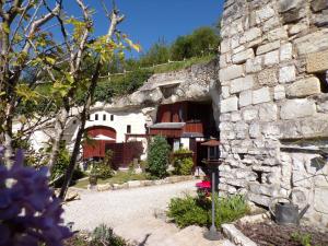 a stone house with a stone wall and a building at Les Troglos de Beaulieu in Loches
