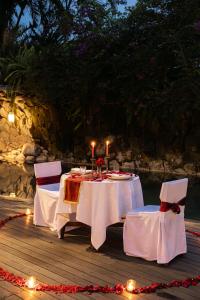 two tables with candles and chairs on a wooden deck at Maca Villas & Spa Bali in Seminyak