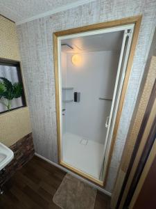 a glass shower door in a bathroom with a sink at YADOKARI miyakojima in Miyako-jima