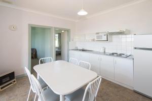 a white kitchen with a white table and chairs at Augusta Hotel Motel in Augusta
