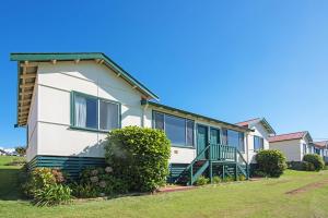 a white house with green windows and bushes at Augusta Hotel Motel in Augusta