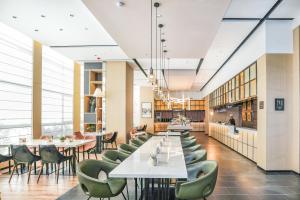 a restaurant with white tables and green chairs at Atour Hotel High Speed Railway North Station Zibo Hi tech Zone in Zibo