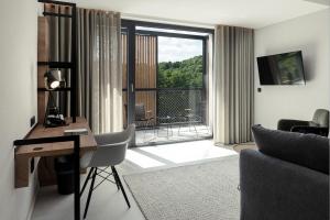 a living room with a desk and a balcony at Hotel VierJahreszeiten am Seilersee in Iserlohn