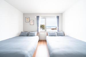 two beds in a room with a window at Stellavia in Nakafurano