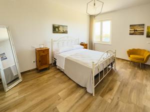 a bedroom with a bed and a mirror and a chair at B&B Il Grande Cipresso Recanati in Castelnuovo