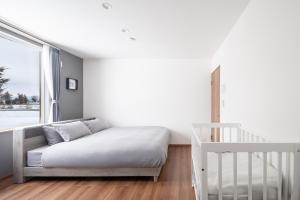 a bedroom with a bed and a crib and a window at Stellavia in Nakafurano