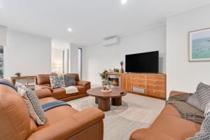 a living room with two couches and a tv at The Hideaway Currumbin in Gold Coast