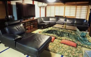a living room with a leather couch and a flat screen tv at 古民家白馬 in Nagano