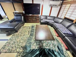 a living room with a leather couch and a flat screen tv at 古民家白馬 in Nagano