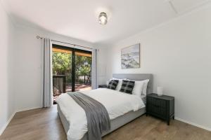 a white bedroom with a bed and a window at Viaggio Sul Mare in Baudin Beach