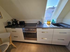 a kitchen with a stove and a sink and a window at Küstenglück 3 Modernes Maisonette-Apartment mit Meerblick & Kickerspaß - 200m zum Strand & Bäcker in Dahme