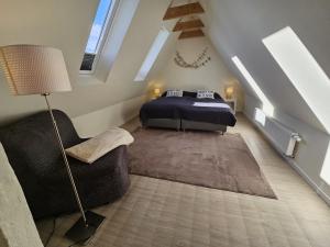 a bedroom with a bed and a chair in a attic at Küstenglück 3 Modernes Maisonette-Apartment mit Meerblick & Kickerspaß - 200m zum Strand & Bäcker in Dahme +22 photos