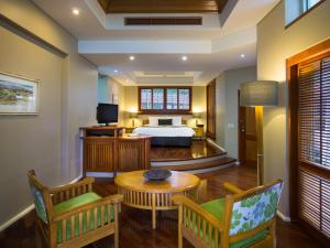 Green Island Resort في الجزيرة الخضراء: غرفة نوم بسرير وطاولة وكراسي