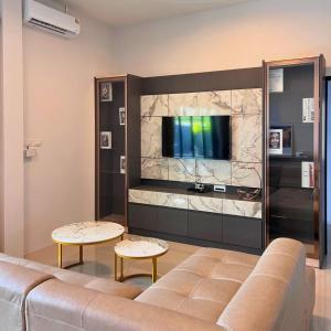 a living room with a couch and a flat screen tv at Aqua Pool villa, Krabi in Ban Nong Thale