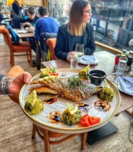 a person holding a plate of fish and vegetables at Konačište Grad B&B in Užice