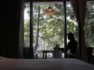 a woman sitting at a table in front of a window at Shishe Spring Designer Homestay in Dujiangyan