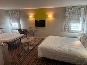 a hotel room with two beds and a flat screen tv at Kyriad Lyon Est - Saint Bonnet De Mure in Saint-Bonnet-de-Mure