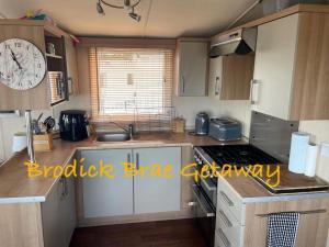 a small kitchen with a clock on the wall at Brodick Brae Getaway in Dunure