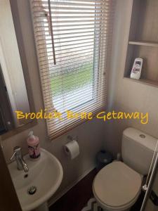 a bathroom with a toilet and a sink and a window at Brodick Brae Getaway in Dunure
