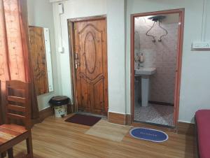 a bathroom with a wooden door and a sink at Joyous Rooms in Cherrapunji +10 photos