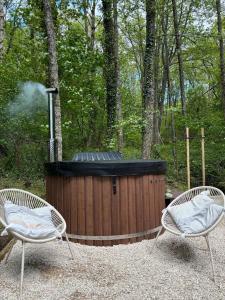 two chairs and a hot tub in the woods at Chalet et étang, exclusivement privée in Manzat