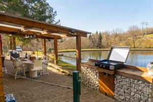 a patio with a table and a grill next to a lake at Chalet et étang, exclusivement privée in Manzat