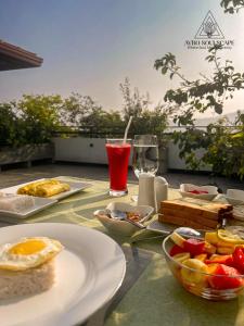 a table with plates of food and a glass of juice at Aybo Soulscape Villa Dambulla in Dambulla