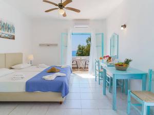 a bedroom with two beds and a table and a dining room at Makrigialos Apartments und Studios in Makry Gialos