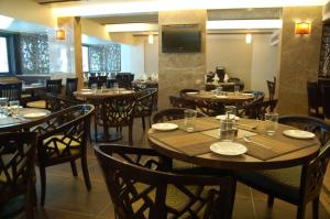 a restaurant with wooden tables and chairs and a television at Comfort Inn President Near Ahmedabad Junction Station in Ahmedabad +20 photos