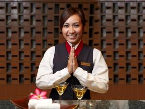 バンコクにあるLe Siam Hotel by PCLの手を上げてテーブルに座る女