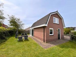 a red brick house with a table and chairs in the yard at Bungalowverhuur 't Lappennest in Noordwijk +78 photos