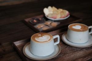 two cups of coffee on a table with a plate of food at Shishe Spring Designer Homestay in Dujiangyan +76 photos