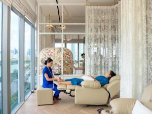 two women sitting in chairs in a room with windows at Wyndham Bangkok Queen Convention Centre in Bangkok