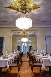 a dining room with white tables and chairs and a chandelier at Hotel Schloss Rabenstein in Chemnitz